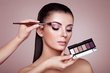 Ein Making off, wo einer Frau mit dunklen langen braunen Haaren ein Augen Make-up geschminkt wird
