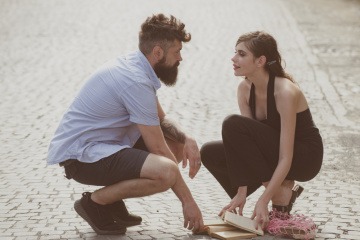Ein Mann und eine Frau gehen auf der Straße in die Knie und schauen sich verliebt in die Augen