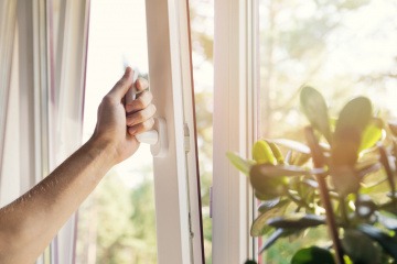 Eine Hand kippt ein Fenster für frische Raumluft