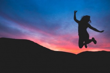 Eine Frau macht im Sonnenuntergang einen Luftsprung