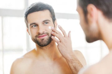 Ein Mann steht vor einem Spiegel für die Männer Gesichtspflege
