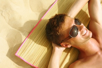 Ein Mann liegt in der Sonne am Strand