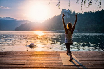Eine Frau meditiert neben einem See in der Natur
