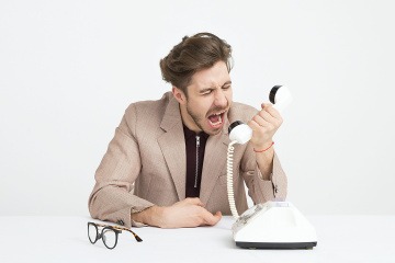 Ein Mann schreit in einen Telefonhörer.