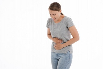 Eine Frau hält sich den Magen und braucht ein Mittel gegen Sodbrennen