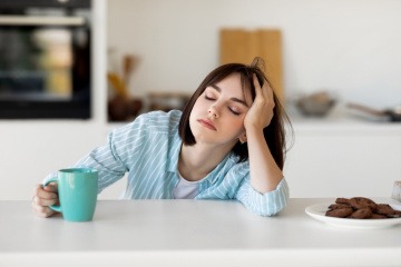 Frau mit Kopf auf dem Schreibtisch.