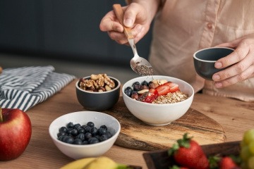 Müsli selber machen - junge Frau nascht aus einer Schale mit selbstgemachtem Müsli.