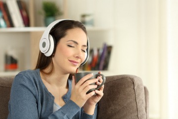 Eine junge Frau hört mit Kopfhörern Musik und genießt es
