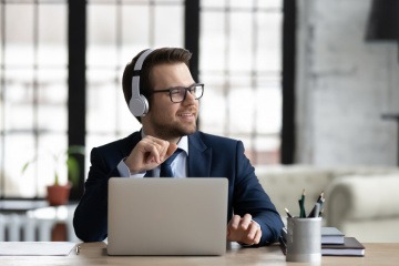 Ein Mann im Anzug hört auf der Arbeit mit Kopfhörern Musik