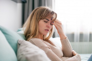 Eine Frau auf einem Sofa scheint negative Gefühle zu unterdrücken