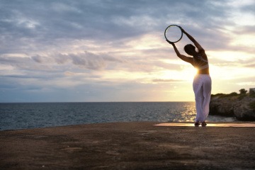Frau im Sonnenuntergang macht Stretching-Übung