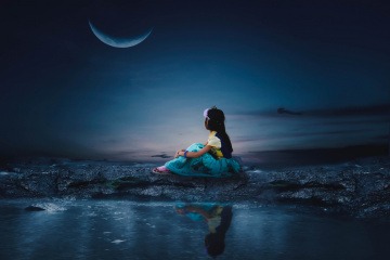 Eine Frau sitzt bei Neumond im September neben Wasser