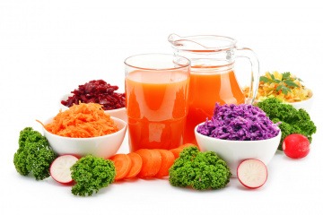 Obst und Gemüse, daneben ein Krug mit orangem Saft
