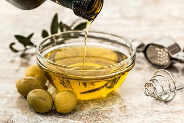 Oliven liegen neben einer Schüssel mit Öl