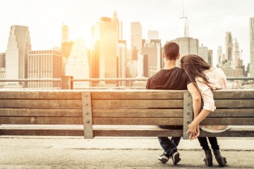 Ein Paar sitzt auf einer Bank vor einer Stadt