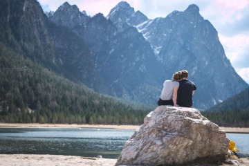 Ein Paar sitzt auf einem Felsen am See und kommuniziert