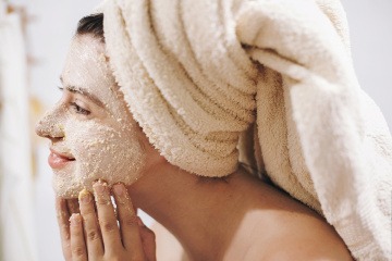 Frau mit Peeling im Gesicht gegen Hautunreinheiten