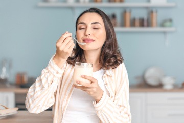 Frau isst Joghurt als probiotisches Lebensmittel