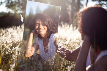 Eine Frau mit reifer Haut sitzt vor einem Spiegel