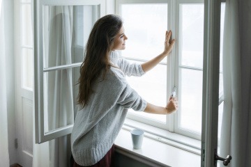 Eine Frau öffnet ein Fenster um richtig zu lüften