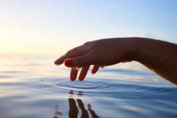 Ruhige Kreise im Wasser werden durch einen Finger gezogen