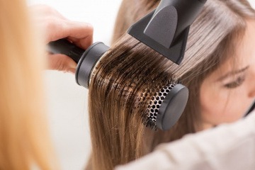 Haare werden mit einer Rundbürste geföhnt
