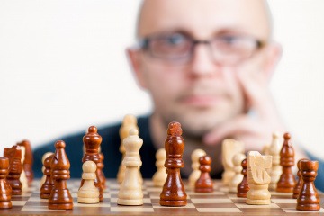 Ein Mann sitzt bei einem Schachspiel und muss denken