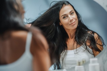 Frau betrachtet ihr Haar im Spiegel