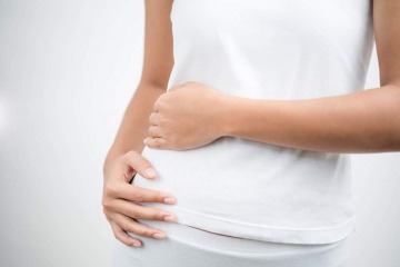 Frau legt die Arme an ihren Bauch,