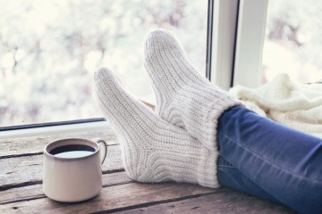 Beine mit Wollsocken sind neben Tee am Tisch
