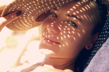 Frau mit Hut und Punkten von der Sonne im Gesicht