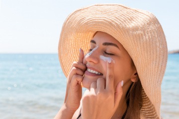 Junge Frau mit Sonnencreme im Gesicht.