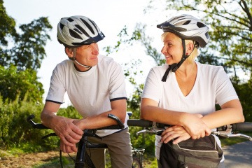 Ältere Menschen betreiben Sport und sitzen am Rad