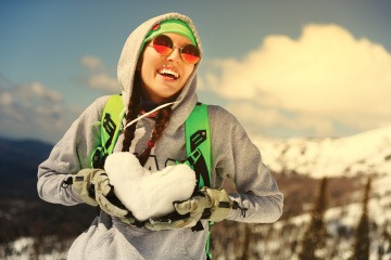 Junge Frau mit Herz aus Schnee in den Händen.