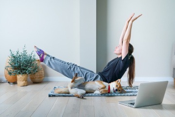 Sport mit Hund - Frau macht mit ihrem Hund Sport im Wohnzimmer.