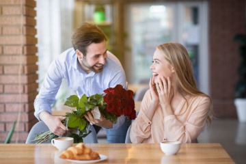 Mann schenkt einer Frau rote Rosen als Zeichen der Liebe
