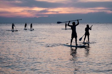 Eine Gruppe von Menschen macht die Trendsportart Stand Up Paddling