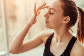 Eine junge Frau tippt sich mit der Fingerspitze auf die Stirn