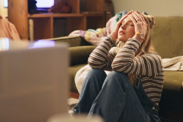 Am Boden sitzende Frau hält gestresst den Kopf 