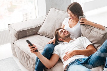 Ein Paar sitzt auf der Couch, die Fernbedienung in der Hand