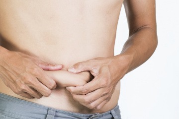 Mann greift Bauchfalte mit Fingern