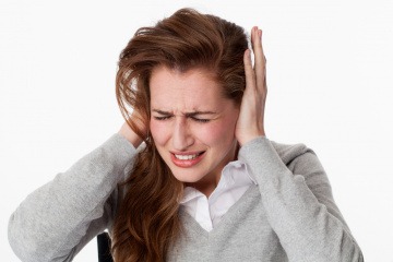 Eine Frau hält sich die Ohren zu und fragt was tun gegen Tinnitus