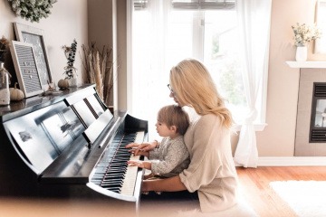 Eine Mutter sitzt mit einem Kind beim Klavier als typengerechte Erziehung