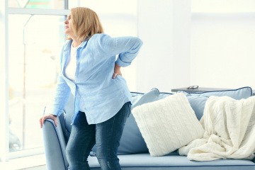 Frau mit Übergewicht hat Rückenschmerzen