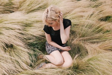 Eine Frau sitzt in wildem trockenen Gras