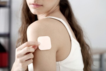 Eine Frau hat ein Verhütungspflaster am Arm