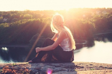 Junge Frau sitzt in der Sonne und kann Vitamin D Mangel beheben