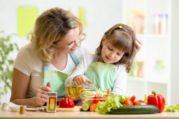Eine Frau bereitet mit einem Mädchen vitaminreiche Ernährung für ein starkes Immunsystem zu