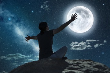 Eine Frau plagt bei Vollmond schlechter Schlaf, sie sitzt nachdenklich auf einer Klippe und blickt zum Mond. 