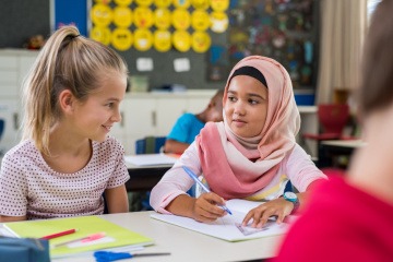 Kinder können am leichtesten Vorurteile abbauen, wie man am Beispiel dieses jungen arabischen Mädchens mit Hidschab bei einer Übung mit ihrer besten Freundin in der Schule sieht.